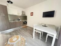 a living room with a white table and a kitchen at Appartement Le Lido de la Marana in Lucciana