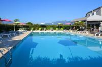 a large swimming pool with chairs and umbrellas at Appartement Le Lido de la Marana in Lucciana