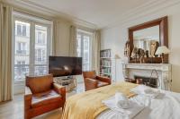 a bedroom with a bed and two chairs and a television at Gorgeous and large flat in the heart of Paris 09 in Paris