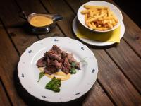 un plato de comida con carne y patatas fritas en una mesa en Hotel Rozkoš, en Česká Skalice