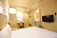 a hotel room with a bed and a flat screen tv at Kindness Hotel - Jhong Jheng in Kaohsiung
