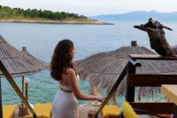 a woman standing in front of the water at Nili Deluxe in Sarandë