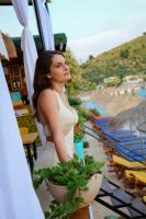 a woman in a white dress standing next to plants at Nili Deluxe in Sarandë