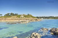 two people in the water near a rocky beach at La plage in Trébeurden