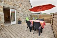 a table and chairs with a red umbrella on a deck at Le four a pain in Pleubian