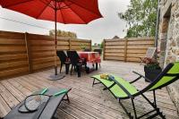 a patio with a table and chairs and a red umbrella at Le four a pain in Pleubian