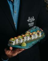 ドス・エルマーナスにあるMare Hotelの寿司の皿を持っているスーツを着た男性