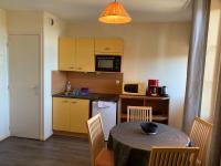 a kitchen with a table with chairs and a microwave at Résidence Le Rochebonne in Saint Malo