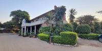 un edificio con árboles y arbustos delante de él en Sunrise Motel, en Lilongwe
