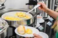 Una mujer sosteniendo un plato con comida en un mostrador. en Silverton Paiva Experience, en Recife