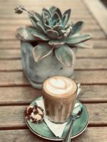 une tasse de café posée sur une table avec un biscuit dans l'établissement Kaijaiki Country Inn and Restaurant, à Yzerfontein