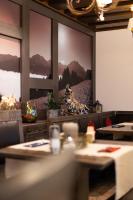 Un restaurante con mesas y vistas a las montañas en la pared. en Haller's Posthotel, en Riezlern