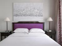 a bedroom with a large white bed with a purple headboard at Hotel Royal Saint Honore Paris Louvre in Paris