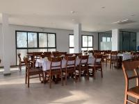 een eetkamer met tafels en stoelen en ramen bij Bờ Biển Vàng Resort in Ke Ga