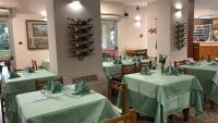Un restaurante con mesas y sillas verdes con botellas de vino. en HOTEL RISTORANTE SAN GIOVANNI, en Falerna