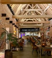 a restaurant with wooden ceilings and tables and chairs at Ferme Delgueule in Tournai