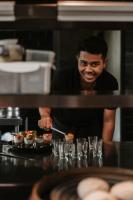 un uomo in piedi dietro un bancone che prepara dei cupcake di East Bali Volcano View Resort & Spa - Adults Only Area a Karangasem