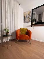 a living room with an orange chair and a table at SSP Suites- Cosy &amp; Bel appartement 4 pièces 3 chambres 90M2 avec balcon in Épinay-sur-Seine