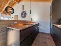 a kitchen with black cabinets and wooden ceilings at Grebenzen Lodge Prinz in Sankt Lambrecht