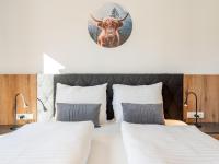 a bedroom with two beds and a deer clock on the wall at Grebenzen Lodge Prinz in Sankt Lambrecht