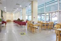 ein Esszimmer mit Tischen, Stühlen und Fenstern in der Unterkunft Grand Hotel Nirvana - All Inclusive & Free Beach Access in Sonnenstrand