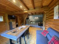 a dining room with a blue couch and a wooden ceiling at LE GRAND CERF Chalet en rondins avec SPA Jacuzzi in La Bresse