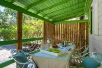 - une table et des chaises sur une terrasse couverte avec une moustiquaire et une table et des chaises dans l&#39;établissement Camping Le Bois Fleuri, à Argelès-sur-Mer