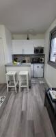 a kitchen with two white stools and a counter at LOGEMENT CLICHY in Clichy