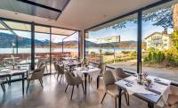 a restaurant with tables and chairs and large windows at Seehotel zur Post in Tegernsee