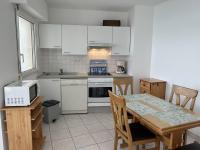 a kitchen with white appliances and a table with chairs at 501 - Appartement 1 chambre à Erquy, à proximité du port, en bordure de la plage du centre in Erquy