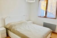a white bedroom with a bed and a window at Pretty triplex with garden and view in Puy-Saint-Pierre