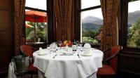 a table in a restaurant with a view of a mountain at Enniskeen Country House Hotel in Newcastle