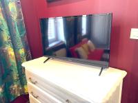 a flat screen tv on a dresser with a red couch at La Domus Lemaitre 1, plain-pied, Wifi , TV, parking, jardin 