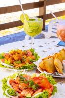 a table with plates of food and a drink at Pousada Estrela da Luz Beach in Ceará-Mirim