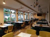 a dining room with tables and chairs and windows at Hotel Pepa in Divčibare
