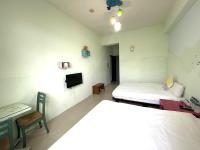 a room with two beds and a table and a tv at 萩閣民宿Sara&#39;s House走路可到夜市近市區好停車 in Hualien City