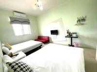 a bedroom with two beds and a red chair at 萩閣民宿Sara&#39;s House走路可到夜市近市區好停車 in Hualien City