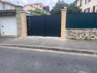 a garage with a black gate and a driveway at Maison Climatisée 04 chambres Paris Disney CDG in Gagny