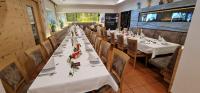 a long table in a restaurant with white tables and chairs at Gasthaus - Pension Kärntnerhof in Faak am See