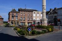 a street with a building with a clock tower and flowers at La Domus Lemaitre 1, plain-pied, Wifi , TV, parking, jardin 