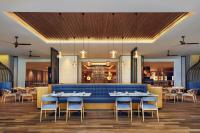 a restaurant with a blue couch and tables and chairs at Four Points by Sheraton Bintan, Lagoi Bay in Lagoi