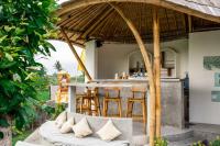 an outdoor bar with a table and chairs under a straw umbrella at Shanti Boutique Retreat in Tanah Lot