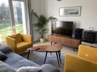 a living room with a flat screen tv and yellow chairs at LE COQ - Maison 10 personnes - Locmariaquer in Locmariaquer