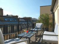 a patio with two chairs and a table on a balcony at Hotel Royal Saint Honore Paris Louvre in Paris