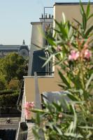 a building with a balcony with pink flowers in the foreground at Hotel Royal Saint Honore Paris Louvre in Paris