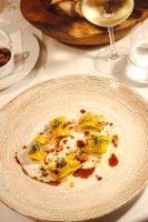 La Meridiana ReIais & Chateaux في غارليندا: طبق من الطعام على طاولة مع كأس من النبيذ