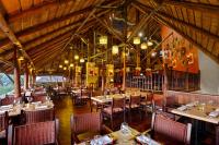 um restaurante com mesas e cadeiras em uma sala em Victoria Falls Safari Suites em Victoria Falls