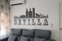 un sofá en la sala de estar con un cartel en la pared en LUISAHOUSE, en el corazón de Sevilla y Triana, en Sevilla
