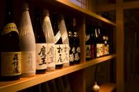 una fila di bottiglie di vino su una mensola di Ryokusuitei a Kamogawa