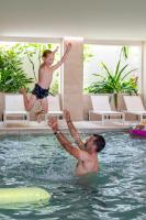 a man and a boy jumping in a swimming pool at Hôtel Helios &amp; SPA - Ile des Embiez in Six-Fours-les-Plages